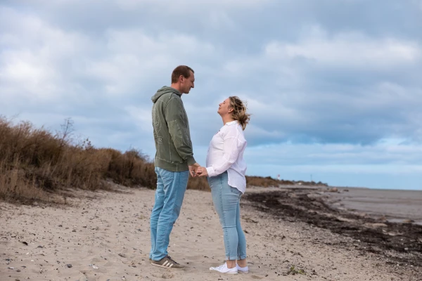 Paar steht am Strand und sieht sich an
