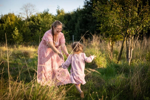 Kleines Kind, 3 Jahre läuft im Feld auf ihre Mama zu. Sie hält ihre Arme offen.