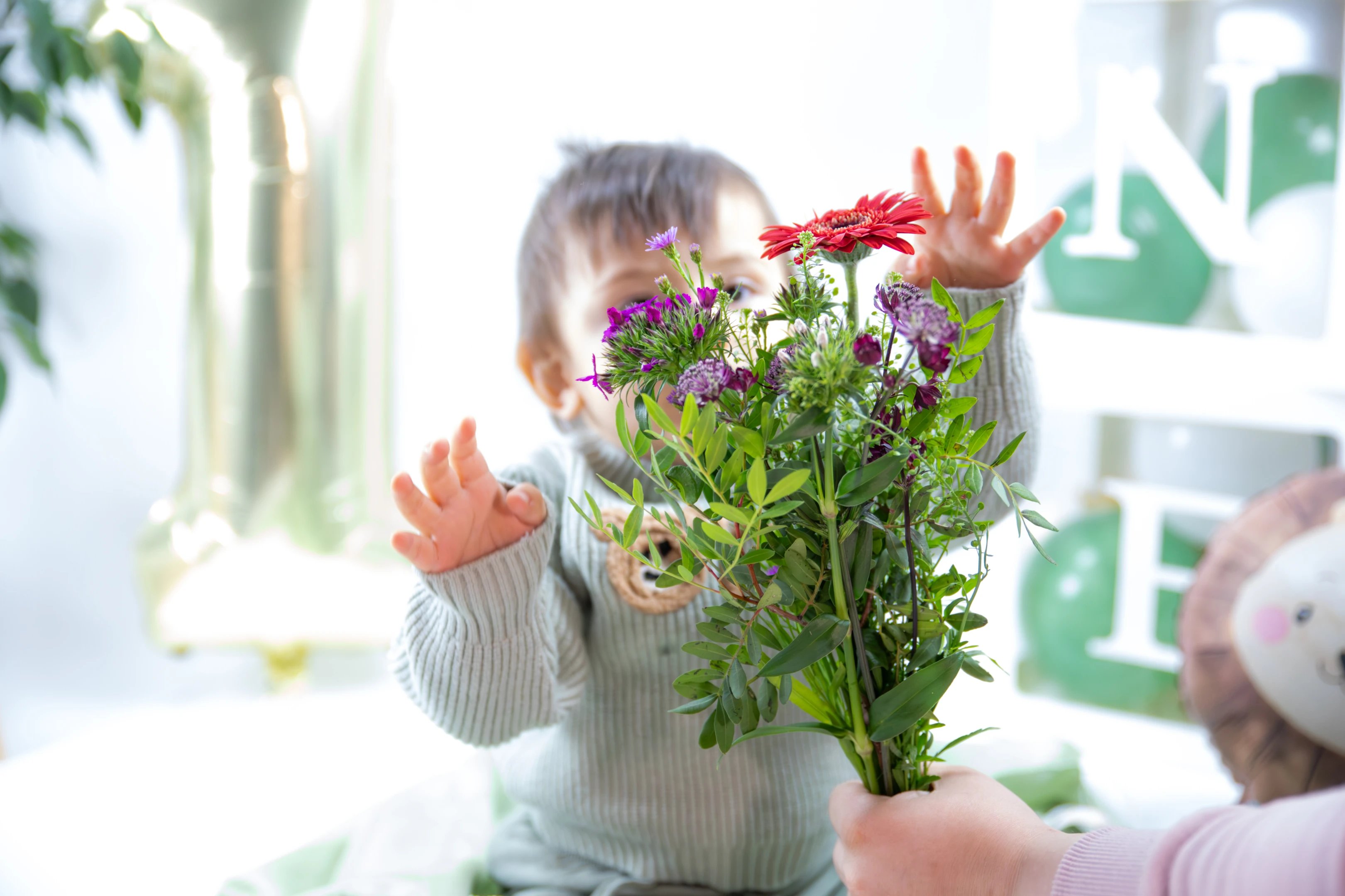 Kind greift nach Blumen, Gesicht hinter Blumen versteckt